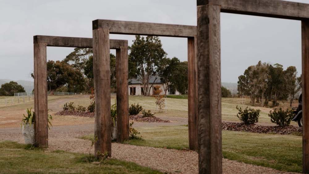Timber arches framing the lawn and the stone homestead at Stockyard Valley